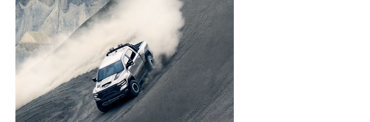 The 2023 Ram 1500 TRX being driven around a banked curve in the desert.