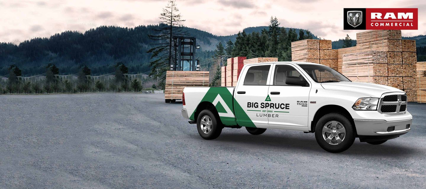 A man loading lumber into the pickup bed of a white 2023 Ram 1500 Classic Tradesman 4x4 Crew Cab. Ram Commercial Truck Season.