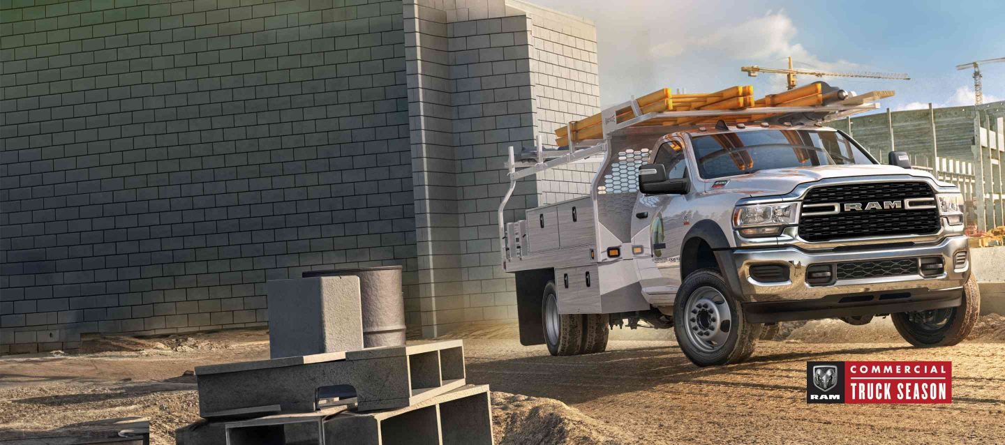 A white 2024 Ram 5500 SLT Chassis Cab with a utility upfit, parked at a commercial construction site.