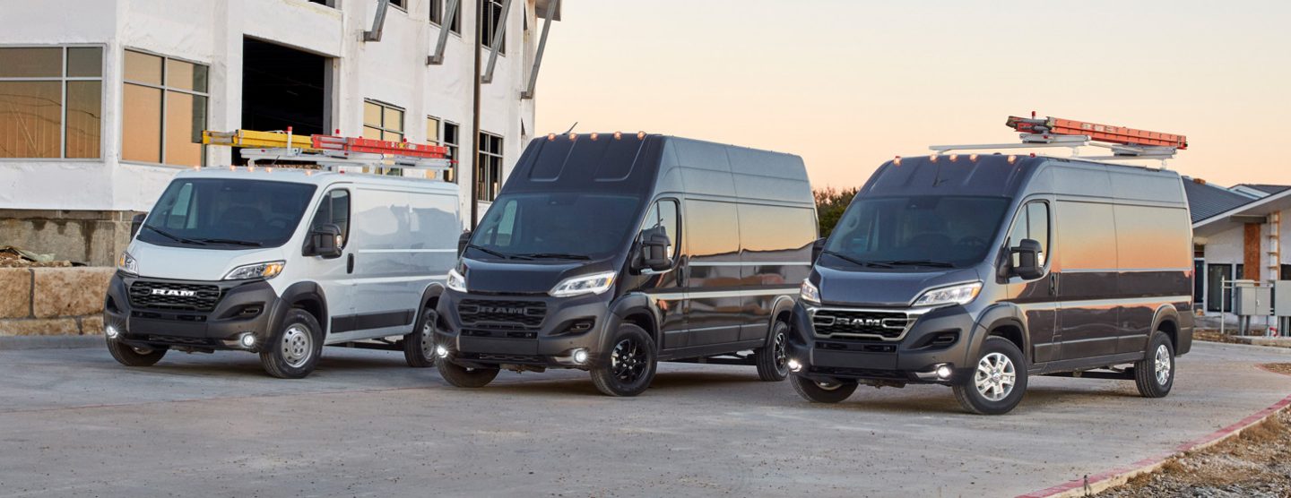 Una alineación de tres furgonetas Ram ProMaster 2025, cada una con una altura de techo diferente, aparcadas en una obra: de izquierda a derecha, una Ram ProMaster 1500 Tradesman Cargo Van Standard Roof blanca, una Ram ProMaster 3500 SLT Plus Cargo Van Super High Roof negra y una Ram ProMaster 2500 SLT Cargo Van High Roof negra.