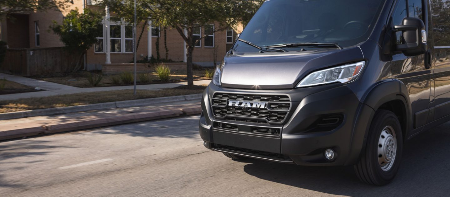 Una Ram ProMaster 2500 Tradesman Cargo Van High Roof negra de 2025 siendo conducida por un barrio residencial