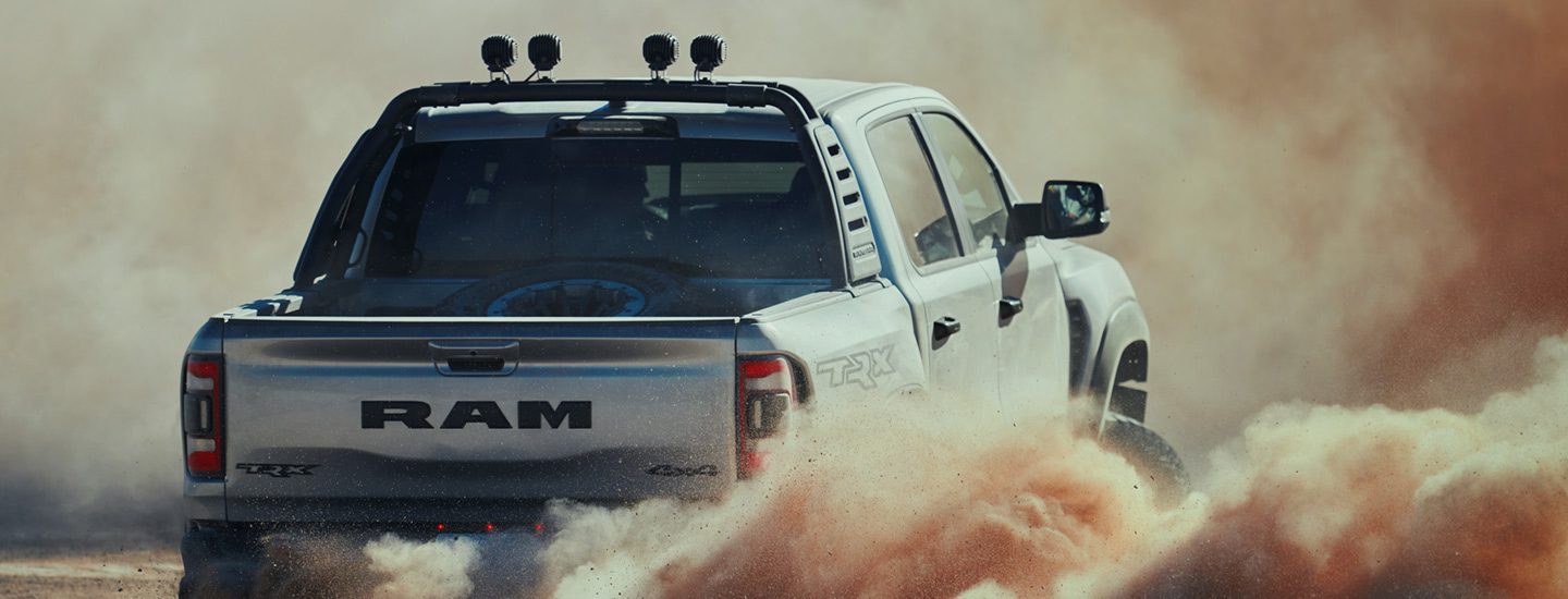 Una visión trasera del Ram 1500 TRX 2023 rodeado de una nube de polvo saliendo de las ruedas.