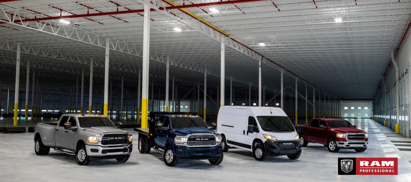 Una línea de cuatro vehículos marca Ram estacionados en un garaje industrial. De izquierda a derecha: una Ram 3500 Big Horn 4x4 Crew Cab 2024 plateada, una Ram 4500 Limited Chassis Crew Cab 2024 azul con mejora de plataforma utilitaria, una Ram ProMaster 2500 Tradesman 159" WB High Roof Cargo Van 2024 blanca y una Ram 1500 Tradesman 4x4 Crew Cab 2024 roja. Temporada de la camioneta comercial Ram.