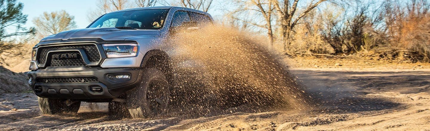 The 2023 Ram 1500 Rebel being driven off-road with dirt spraying up from its wheels.