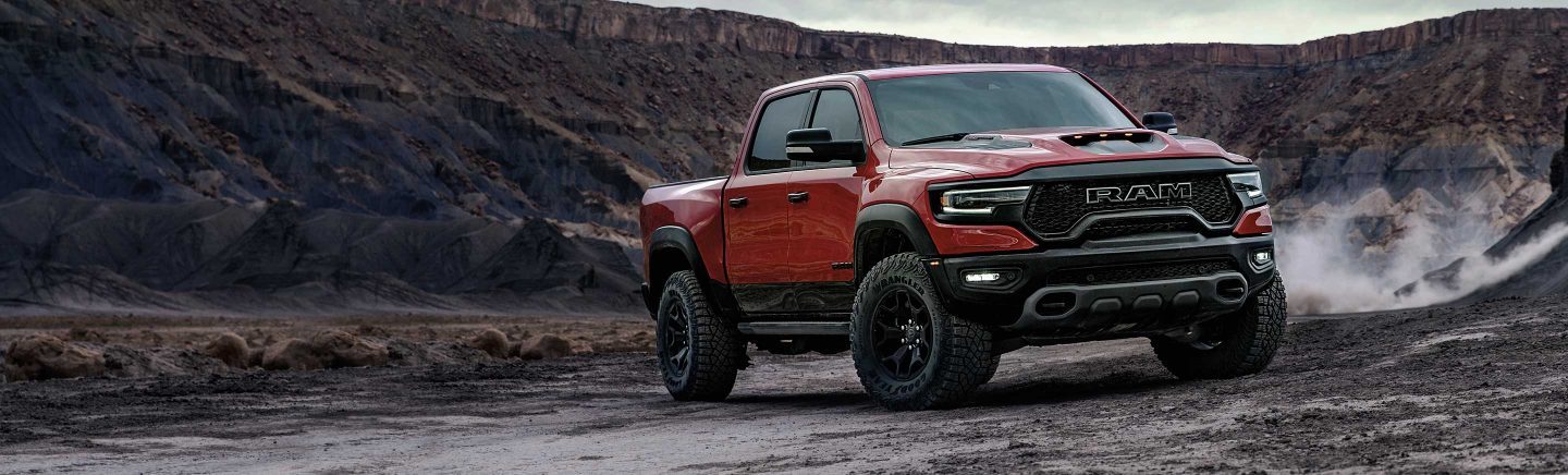 The 2023 Ram 1500 TRX parked off-road at the base of a tall plateau.